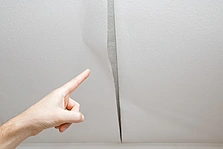 ansatzfrei - Mannes Hand Fingerzeig auf das Problem. Alte Tapete von der Decke in den Raum abziehen. - Stock-Fotografie